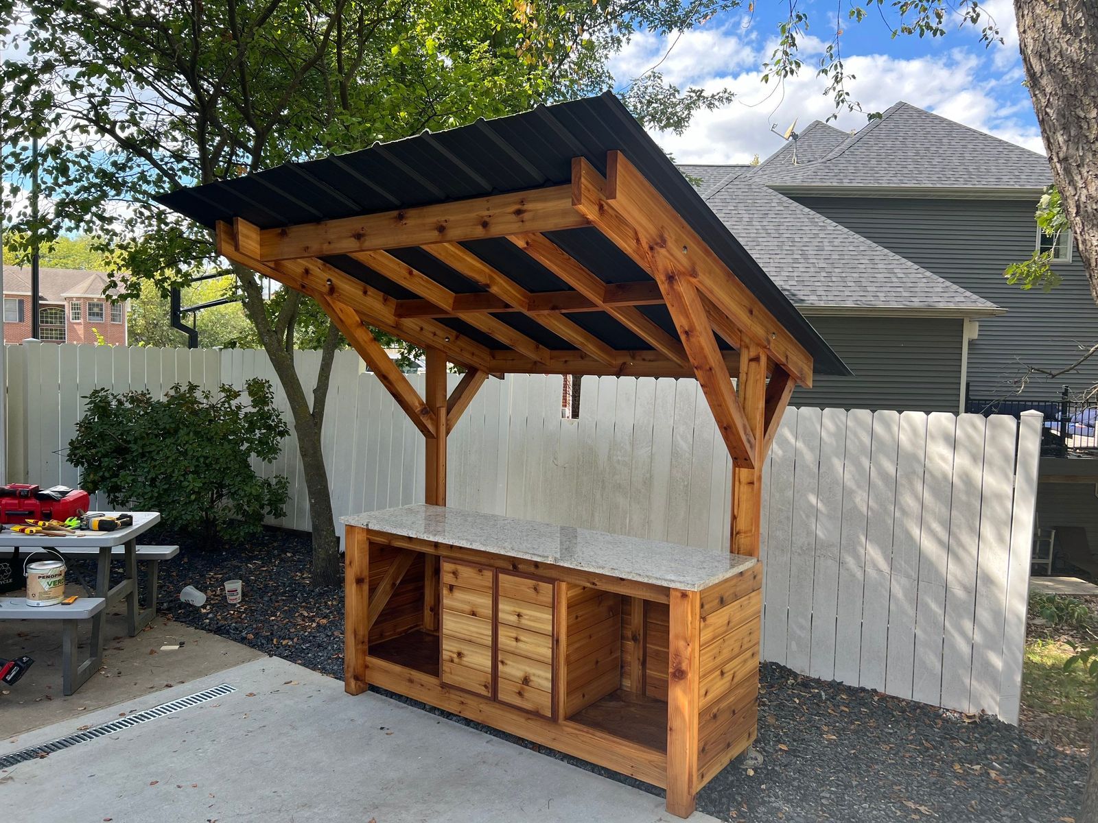 Custom outdoor kitchen with cedar accent and a standing seam metal canopy